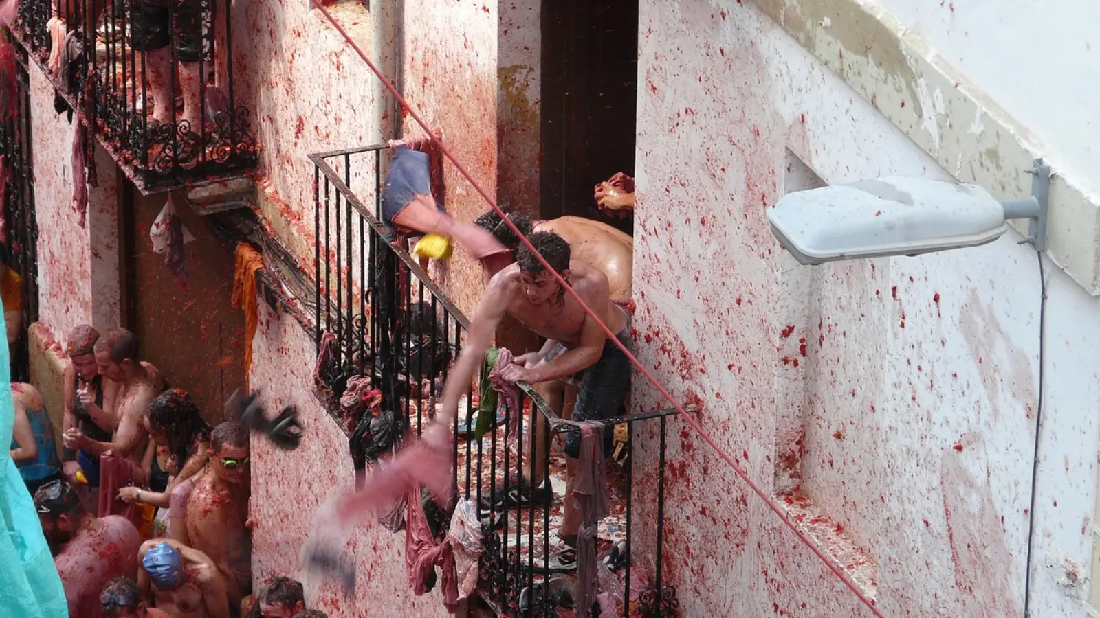 La Tomatina participants rinsing tomato pulp from a narrow street in Buñol